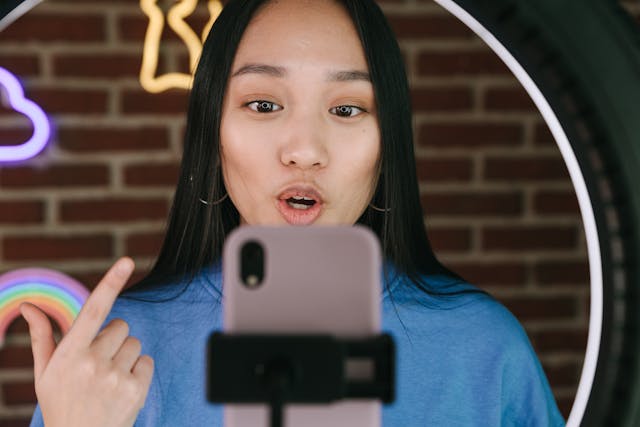 Dark-haired woman filming herself with a smartphone.